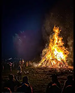 A burning bonfire of a towering 30 foot wickerman holding a sword. A crowd watches from below.