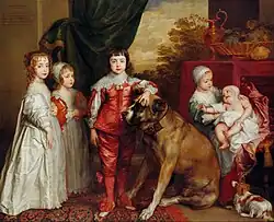"Portrait of five children dressed in satin clothing of the 16th century, from the left a girl in white, a boy in dress and bonnet, and a regal-looking boy in red breeches in the centre. To the right is a younger girl sitting holding a baby in her arms. A large brown mastiff dog sits in the middle next to the boy and a small white and brown spaniel is in the bottom right."