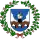 A coat of arms depicting a brown bridge rising up out of a blue body of water into a blue sky with white clouds