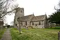 Stone building with prominent square tower. In the foreground are gravestones.