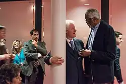 Clinton smiling and hugging a pole while speaking to Russell