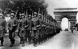 Soldiers walking down Champs-Élysées, with Arc de Triomphe in the back