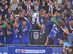 A football team celebrating with a trophy