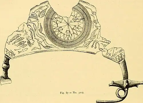 The earliest known depiction of the Trojan Horse,[29] on a bronze fibula (ca. 700 BC), partially visible to the right of the center rosette. Note the wheels and the square openings on the horse's side.