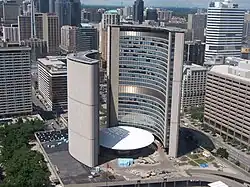 Two curved tower building around a circular small white building.