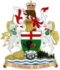 A central shield showing a bison standing on a rock, under a St George's Cross. On top of the shield sits a helmet decorated with a red and white billowing veil. On top of the helmet sits a beaver with a crown on its back, holding a prairie crocus. To the right of the shield is a rearing white unicorn wearing a collar of white and green maple leaves, from which hangs a green cart-wheel pendant. To the left of the shield is a rearing white horse wearing a collar of Indian beadwork, from which hangs a green cycle of life medallion. The animals and shield stand on a mound, with a wheat field beneath the unicorn, prairie crocuses beneath the shield, and spruces beneath the horse. Beneath the mound are white and blue waves, under which is an orange scroll bearing the words "GLORIOSUS ET LIBER"