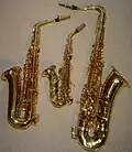 Comparison in size of a curved B♭ soprano saxophone (center), an E♭ alto saxophone (left), and a B♭ tenor saxophone (right)