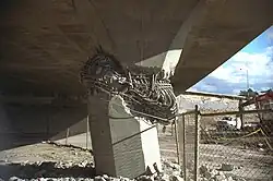 A collapsed concrete bridge, with a broken support pier.