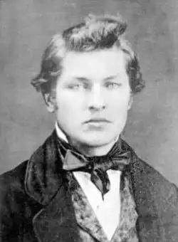 An unsmiling young Garfield with curly hair wearing a three piece suit