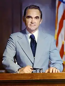 Official portrait of Wallace, wearing a light blue suit jacket, white shirt, and dark blue necktie.
