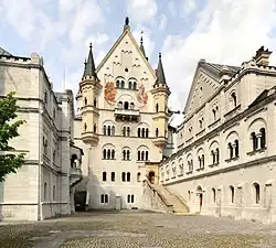 View from location of unrealised chapel along upper courtyard level: Bower (left, with balcony of Elsa von Brabant), palace front, and Knights' House (right), according to Wagner's stage directions for Antwerp Castle in the second act of Lohengrin