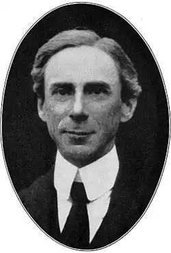 Black and white photo of a man wearing a dark suit, a white shirt, and a tie