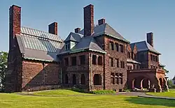 A reddish-brown three-story stone mansion with several chimneys