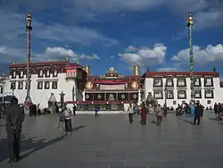 Ornate temple, with two poles and people in a courtyard