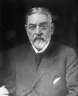 Elderly man in suit seated at desk