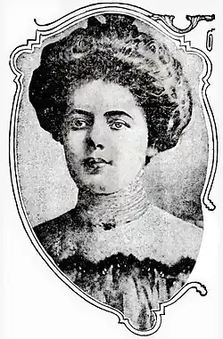 Mallon, looking just left of camera. Her hair is made up on top of her head and she wears a high-necked blouse