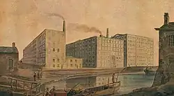 A watercolour of mills with smoking chimneys painted from the opposite side of a river. There is a wooden dock on the left hand side with a small wooden boat by the dock, floating perpendicular to the river.