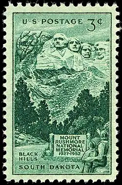 Green 3-cent postage stamp showing people looking at Mount Rushmore