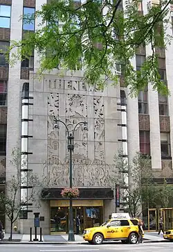 The main entrance on 42nd Street in 2008. The three-story-tall entrance is clad in granite and spans five bays. Over the entrance is a carving of the phrase "The News", below which is a large bas-relief with carvings of people and the phrase "He Made So Many of Them", all in capital letters.