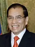 a man with greying black hair, wearing a suit and tie