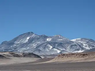 Photo: A broad, irregular mountain in an unvegetated landscape with sparse snowpatches