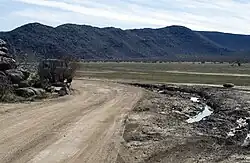 Photograph of deep ruts left by a vehicle that left a posted trail