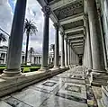 A long colonnaded portico with a patterned marble floor beside the basilica's courtyard.