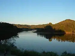 A lake with a forest in the background, which is reflecting upon the water.