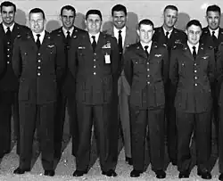 Nine member, eight in uniform, standing for a class photo.