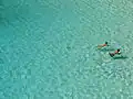 Cyan is the color of shallow water over a sandy beach. The water absorbs the color red from the sunlight, leaving a greenish-blue color.