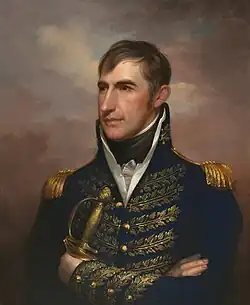 A slightly built man with brown hair wearing a black jacket with gold epaulets and leaf details, a white shirt, and a black tie, holding a sabre in his left hand