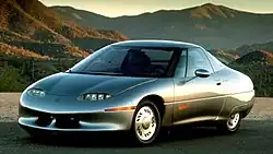 An unusually shaped concept car, taken in a mountainous environment with the sun setting.