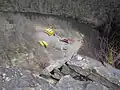 View from above of a curving river in a rocky gorge, several school buses and trucks towing trailers with boats and rafts are parked on a gravel area at left