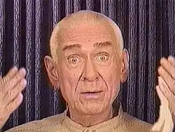 A wide-eyed man addressing a camera