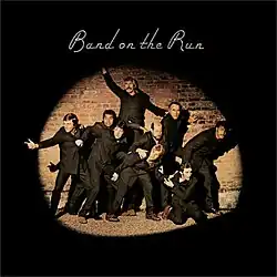 A group of people in black outfits being caught by a spotlight.